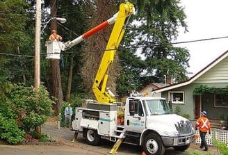 Man in a bucket truck servicing trees around power lines